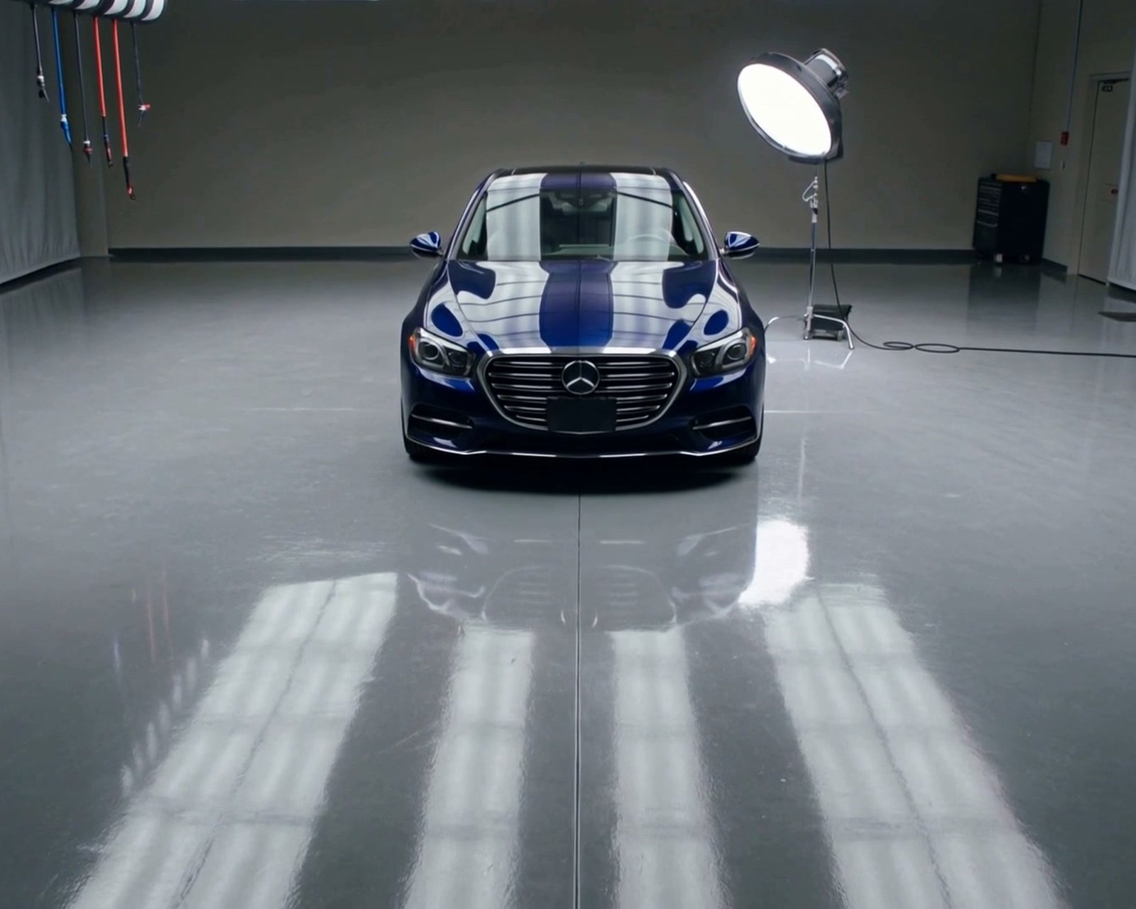 Dark blue car under studio lights in the detailing bay